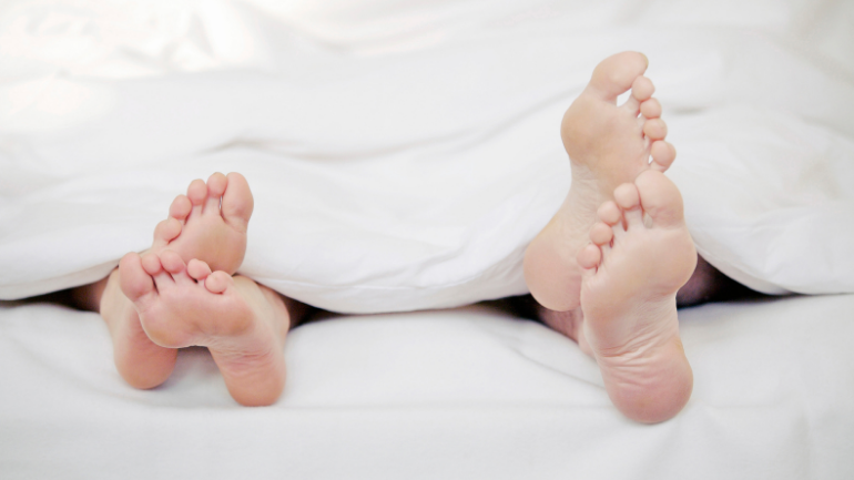 heterosexual couple barefoot in bed